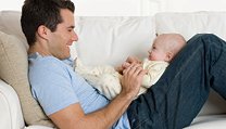 father sitting with infant on couch